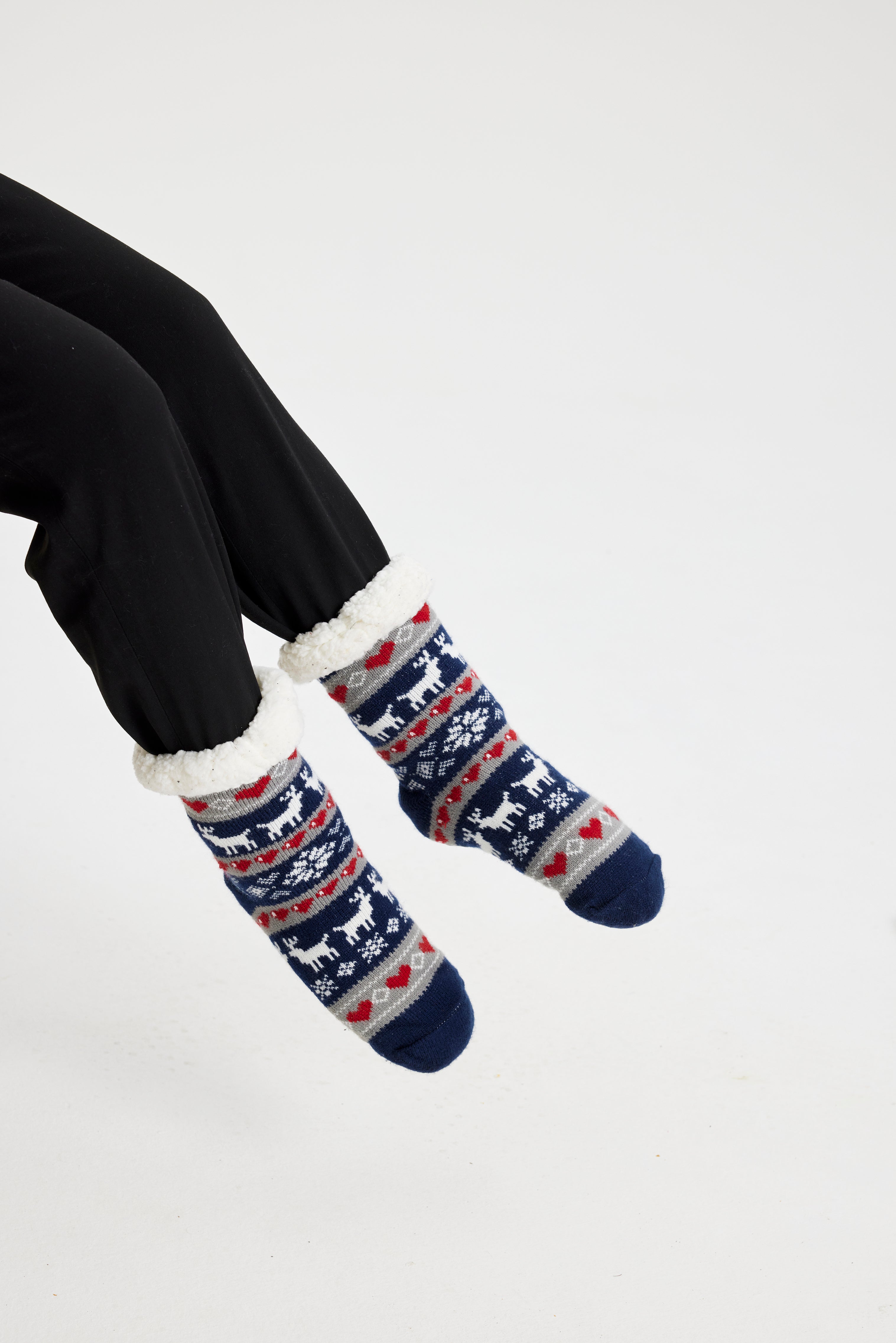 Ein Paar Beine, die ein Paar blaue und weiße Weihnachtssocken mit einem Weihnachtsmuster tragen.